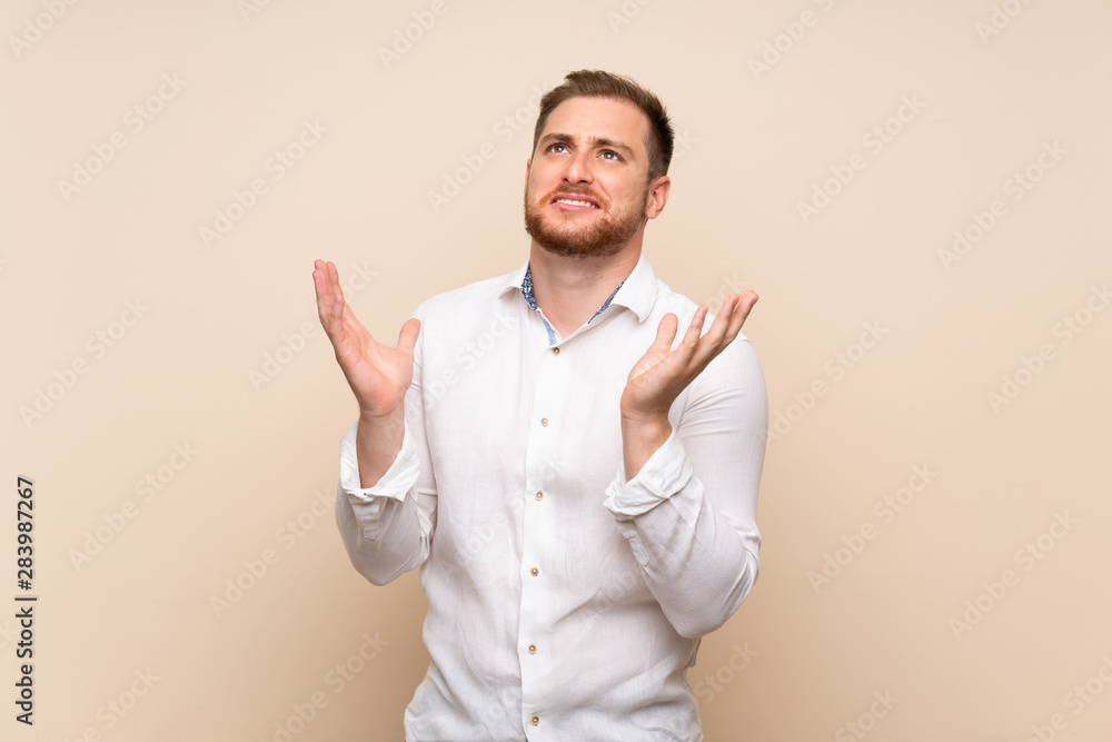 Blonde man over isolated background frustrated by a bad situation Blonde man over isolated background frustrated by a bad situation