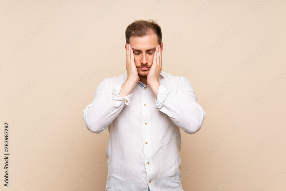 Blonde man over isolated background with headache Blonde man over isolated background with headache