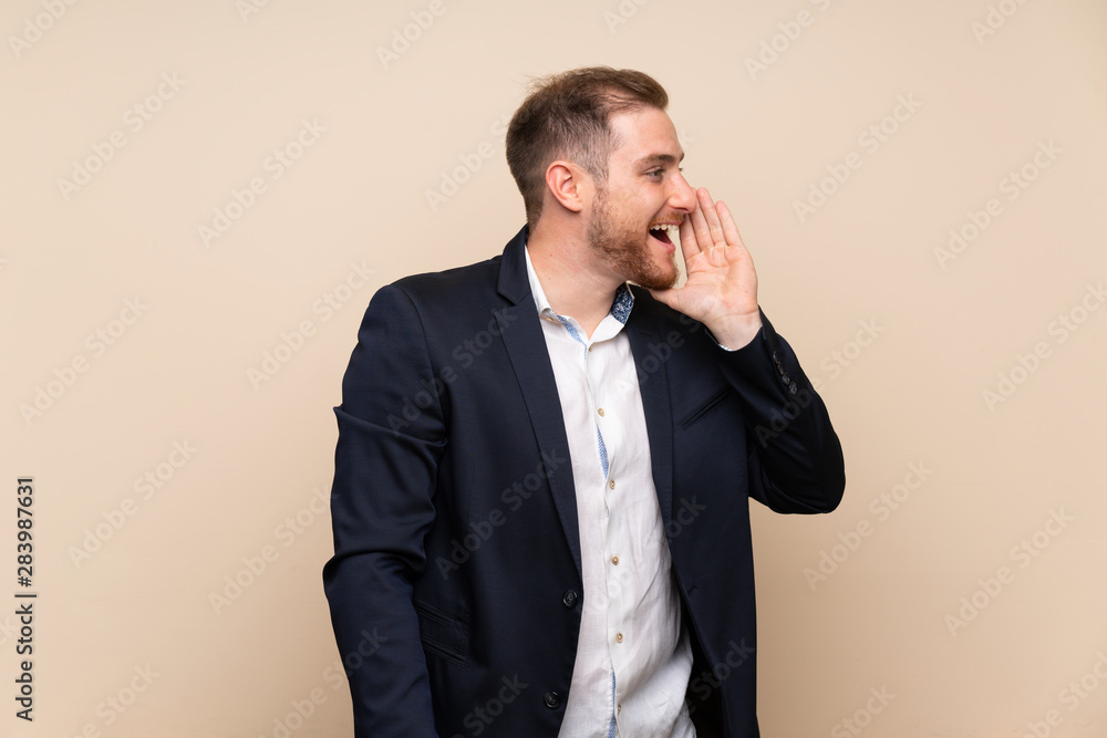 Blonde man over isolated background shouting with mouth wide open to the lateral Blonde man over isolated background shouting with mouth wide open to the lateral