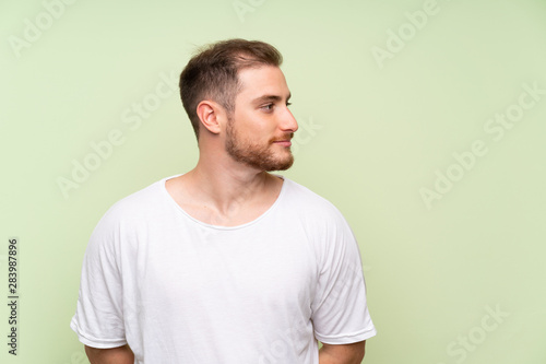 Handsome man over green background looking to the side