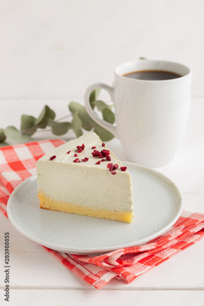 Piece of cheesecake on gray plate on kitchen spatula and cup of coffee on background Piece of cheesecake on gray plate on kitchen spatula and cup of coffee on background