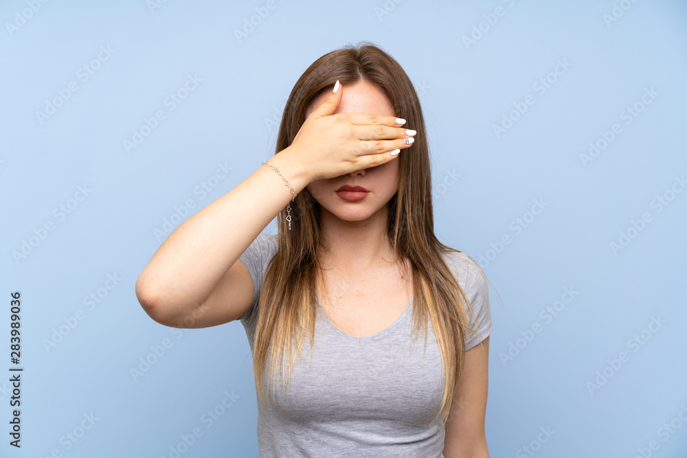 Fototapeta premium Teenager girl over isolated blue wall covering eyes by hands. Do not want to see something