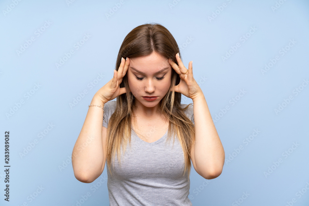 Teenager girl over isolated blue wall with headache Teenager girl over isolated blue wall with headache