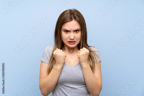Teenager girl over isolated blue wall frustrated by a bad situation