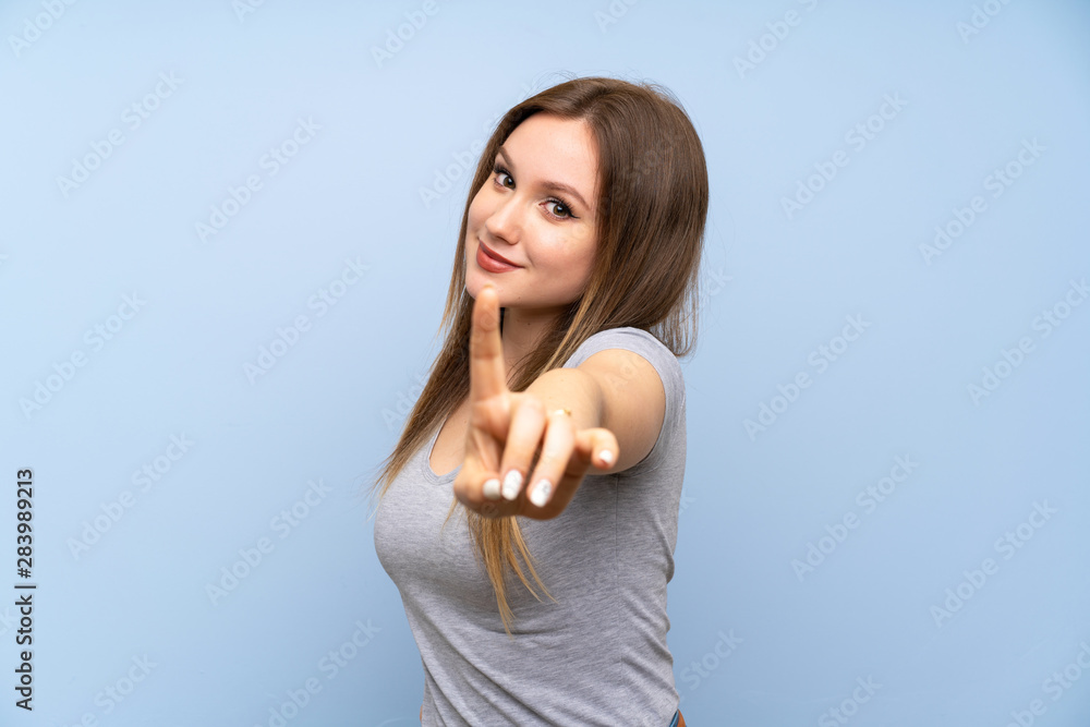 Teenager girl over isolated blue wall showing and lifting a finger Teenager girl over isolated blue wall showing and lifting a finger