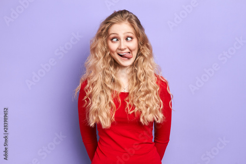crazy mad woman makes funny face, crosses eyes and sticks her tongue out , plays fool, being in good mood. happiness, woman having fun in the studio