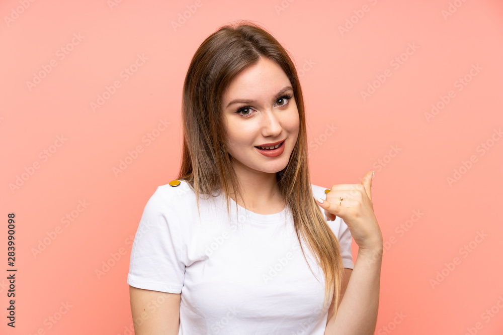 Teenager girl over isolated pink wall making phone gesture Teenager girl over isolated pink wall making phone gesture