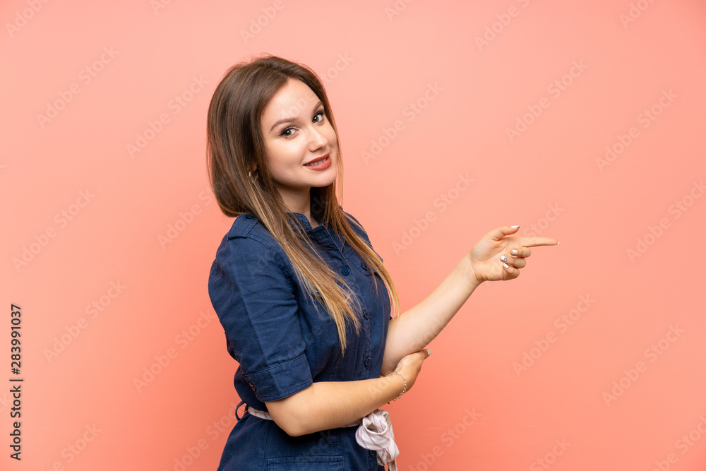 Teenager girl over isolated pink background pointing finger to the side Teenager girl over isolated pink background pointing finger to the side