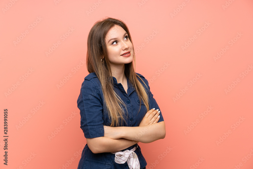 Teenager girl over isolated pink background looking up while smiling Teenager girl over isolated pink background looking up while smiling