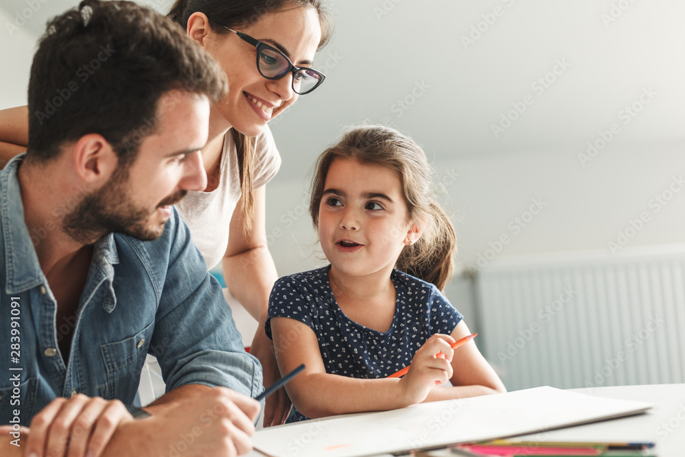 Father and mother teach daughter to draw.They sitting in living room.Education and family concept. Father and mother teach daughter to draw.They sitting in living room.Education and family concept.