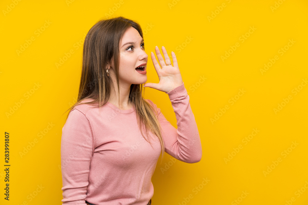 Teenager girl over isolated yellow background shouting with mouth wide open Teenager girl over isolated yellow background shouting with mouth wide open