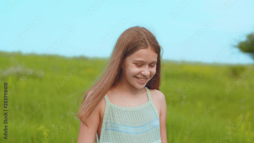Slow motion of joyful smiling little teenage girl enjoying her walk on meadow of blooming wildflowers and high-grass, having fun. Positive emotions, good mood, happy childhood concept Slow motion of joyful smiling little teenage girl enjoying her walk on meadow of blooming wildflowers and high-grass, having fun. Positive emotions, good mood, happy childhood concept