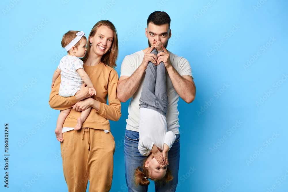Loving husband and wife spending funny time with their kids. isolated blue background. studio shot.copy space - obrazy, fototapety, plakaty 