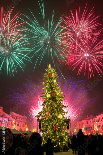 New Year`s Eve firework behind Christmas tree. Celebrating 2019 in Banska Bystrica, Slovakia. Multicolor explosion on dark sky. Foundation day of Slovak republic #284001889