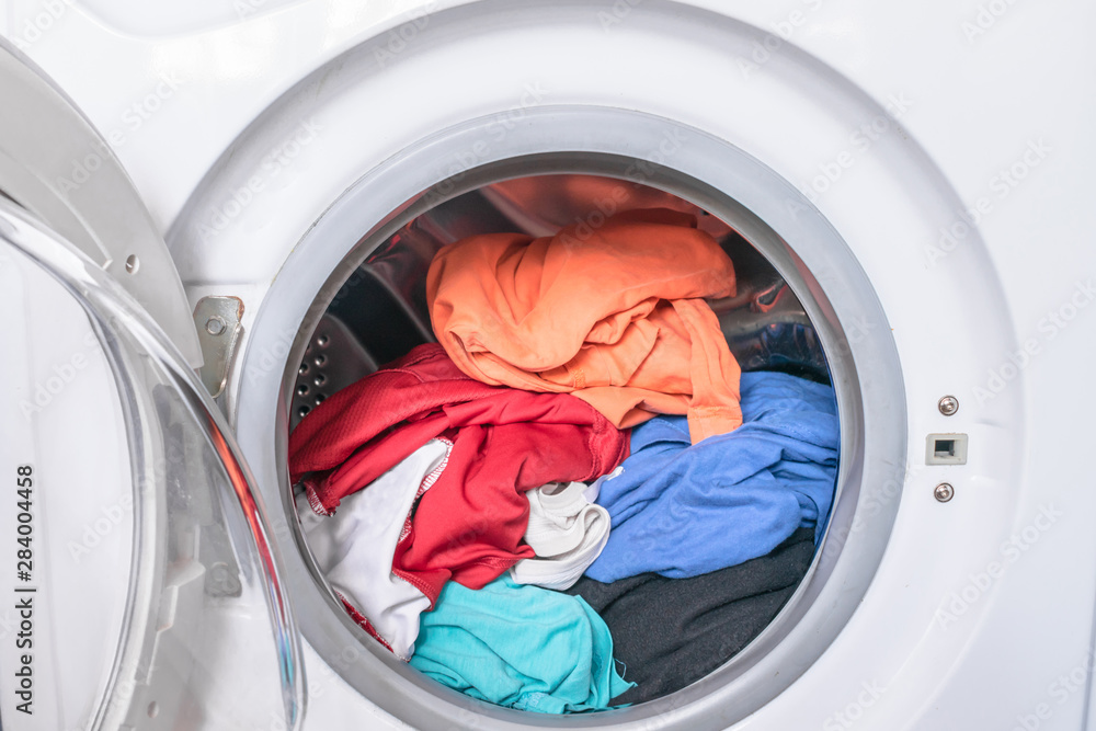 Dirty clothes are inside the washing machine. Automatic washer with open door. Erasing home t-shirts. Dirty clothes are inside the washing machine. Automatic washer with open door. Erasing home t-shirts.