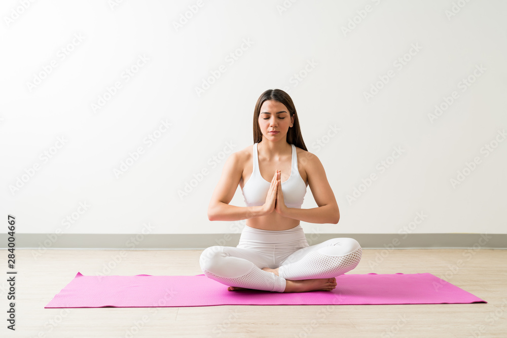 Fit Woman Sitting In Easy Pose Against Wall Fit Woman Sitting In Easy Pose Against Wall