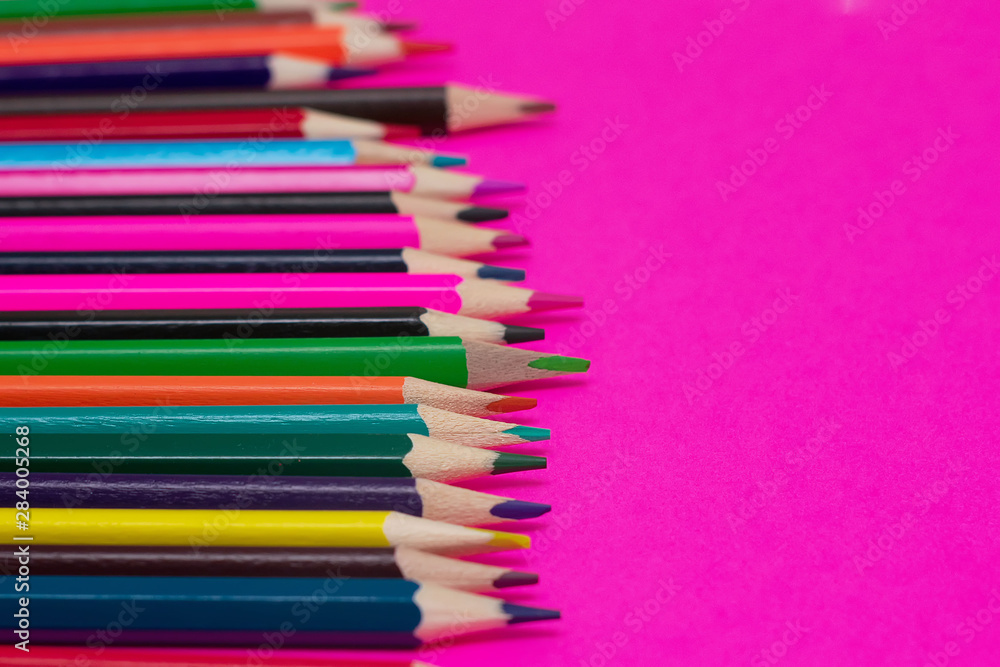 Many colored pencils lie on a pink background. Copy spase. The concept of back to school, the educational process, study at school, drawing Many colored pencils lie on a pink background. Copy spase. The concept of back to school, the educational process, study at school, drawing