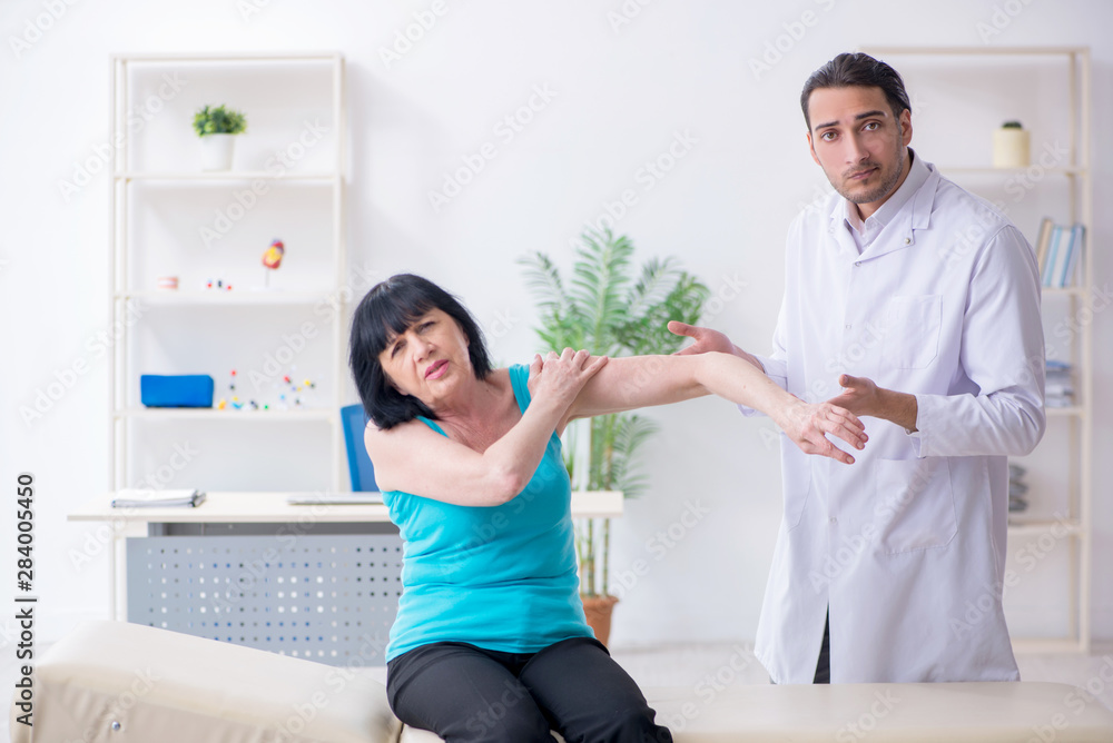 Young male doctor examining old female patient Young male doctor examining old female patient