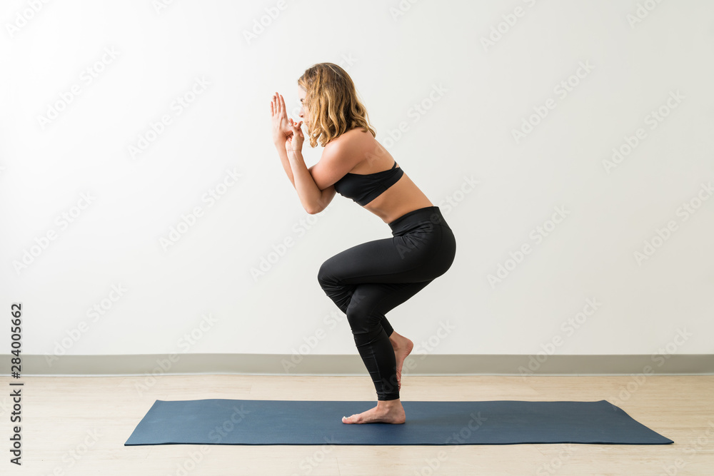 Female Is Practicing Tree Pose On Mat Female Is Practicing Tree Pose On Mat