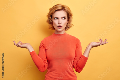 Fotografie puzzled girl looking away, choosing clothes, making up a plan, isolated yellow background