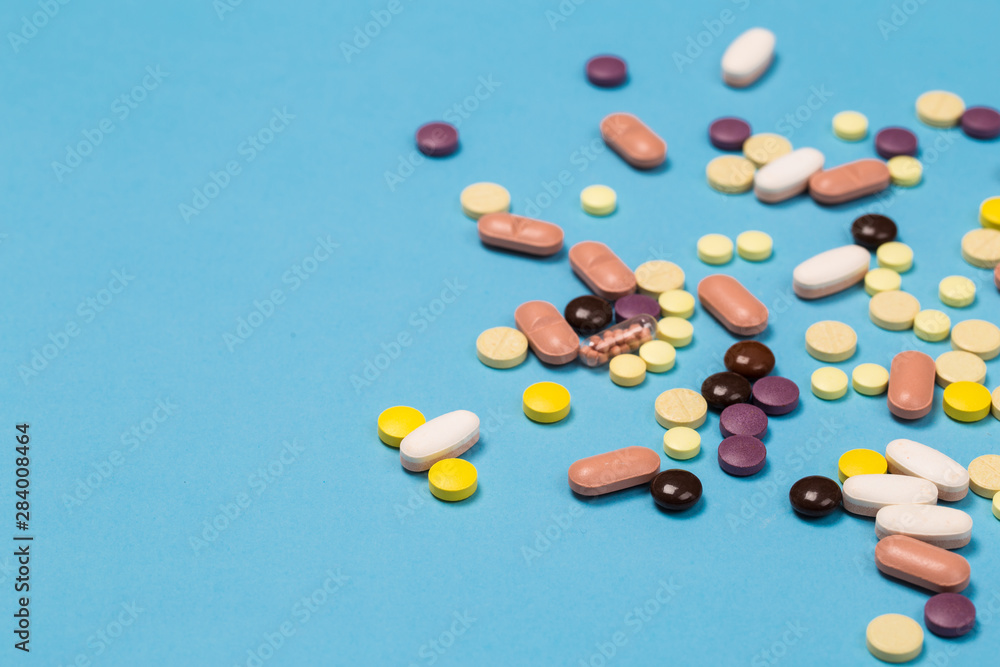 many scattered Colorful medical pills on pastel blue background many scattered Colorful medical pills on pastel blue background