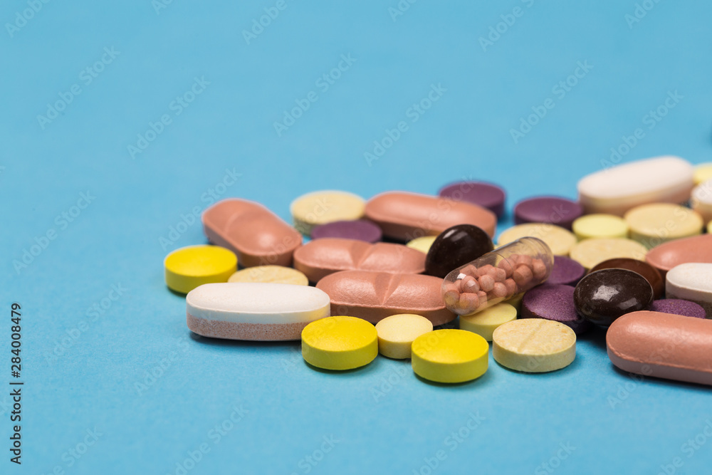 many scattered Colorful medical pills on blue background. Pills are scattered over a blue background. Close up. Medical background. many scattered Colorful medical pills on blue background. Pills are scattered over a blue background. Close up. Medical background.