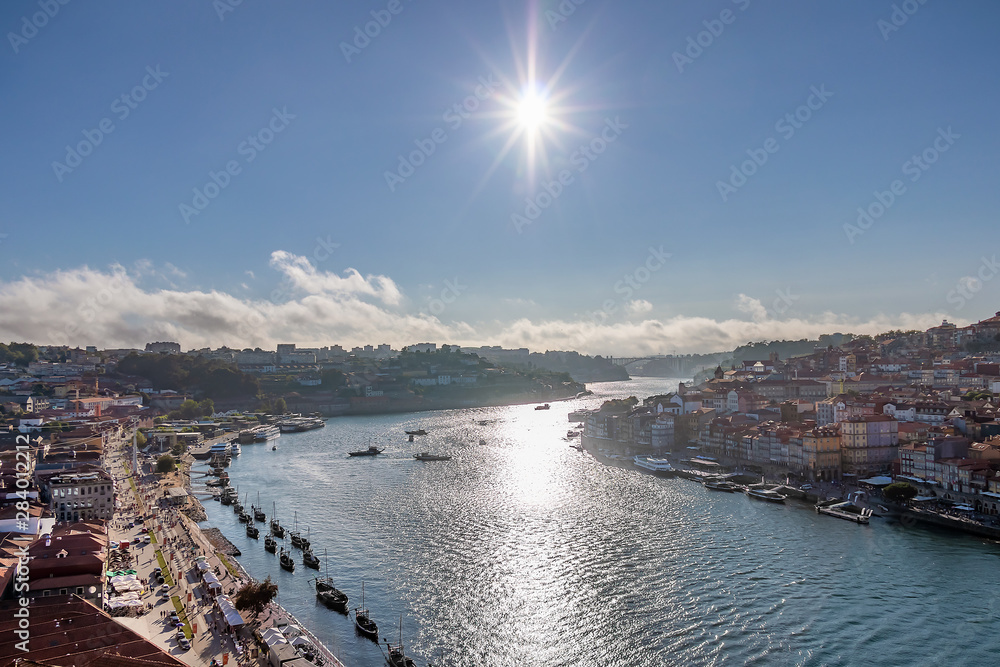 View of the historic city of Porto, Portugal in the right side of Douro river and Vila Nova de Gaia in the left side with the sun light against blue sky