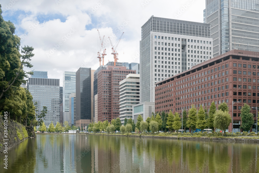 Urban background with Tokyo downtown Marunouchi business district city scape and water reflections of trees and buildings in summer day illustration urban and ecology concept.