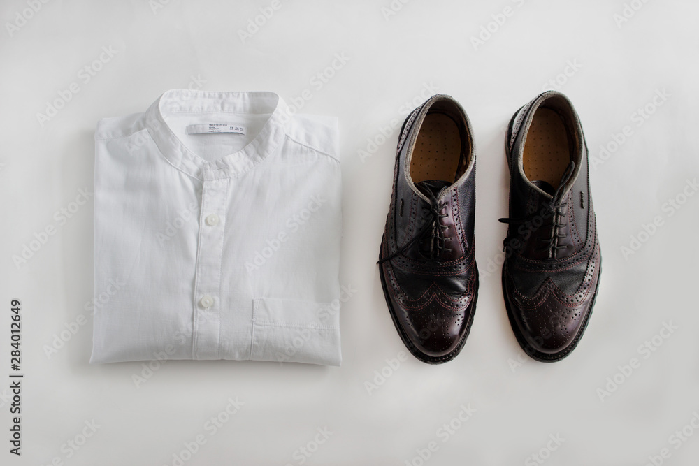 Male outfit set on white background. Shirt and shoe. Close-up, top view Male outfit set on white background. Shirt and shoe. Close-up, top view