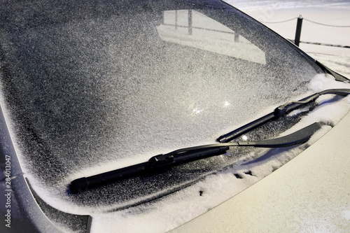 Car windshield in the snow in the evening under the light of a lantern