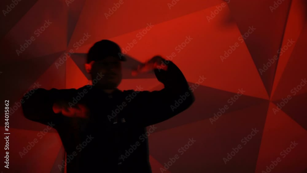 Rapper man dancing to the music. Silhouette on a dark red background Rapper man dancing to the music. Silhouette on a dark red background