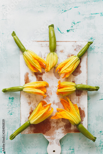 Courgettes with flowers on an old chopping board. Top view  blank space