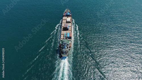 Light loaded container ship sail at sea waters, aerial shot from stern side. Camera tilt up to follow cargo vessel motion. Nice turquoise waters of Ma Wan Channel