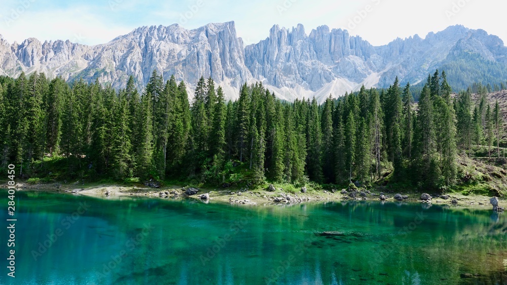 Berge und Bäume spiegeln sich im grünen Karersee in Südtirol