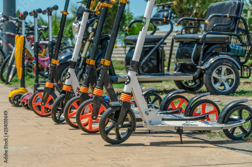 electric scooters stand in a row on the street, rent electric scooters