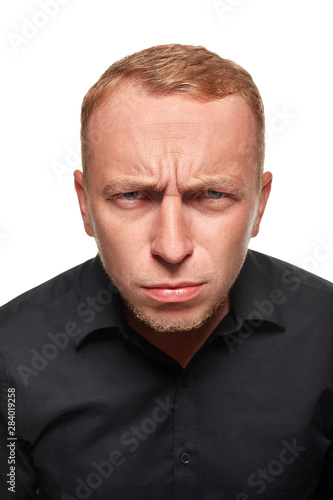 Portrait of young man questionably mistrustfully looking with lowered eyebrows on white background. photo