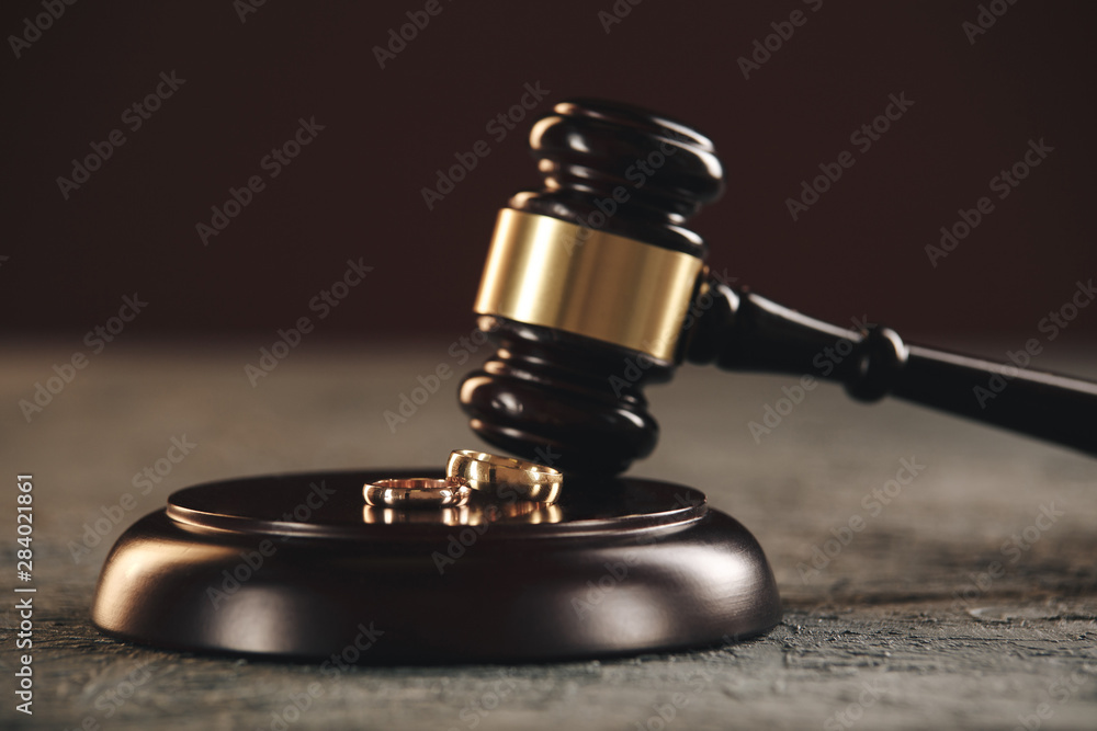 Wedding rings on the figure of a broken heart from a tree, hammer of a judge on a wooden background. Divorce proceedings Wedding rings on the figure of a broken heart from a tree, hammer of a judge on a wooden background. Divorce proceedings