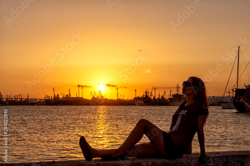 silhouette of woman sitting on a bench at sunset