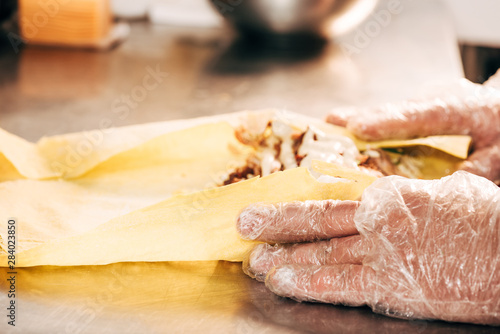 partial view of cook in gloves preparing doner kebab