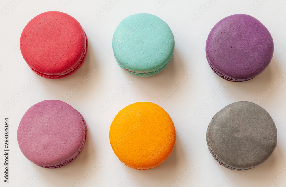 Multi-colored macaroons on a white background, french cookies as a treat for the holiday, top view Multi-colored macaroons on a white background, french cookies as a treat for the holiday, top view