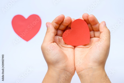 St. Valentine's Day. Heart cut out of paper in the hands of a child on a white background.