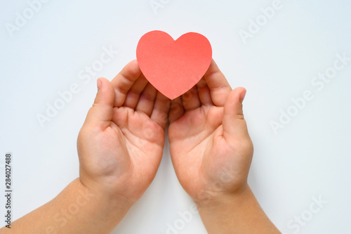 St. Valentine s Day. Heart cut out of paper in the hands of a child on a white background.