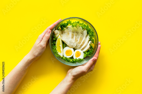 meal in bowl in hands for lunch on yellow background top view