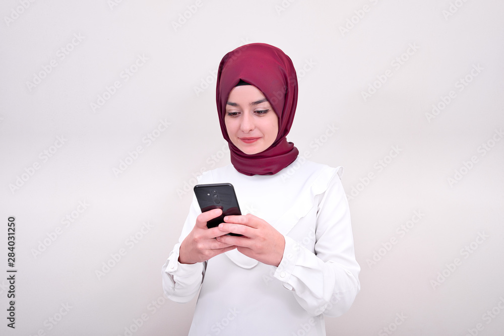 Muslim woman typing text message on smart phone, muslim girl in hijab and she write message Muslim woman typing text message on smart phone, muslim girl in hijab and she write message