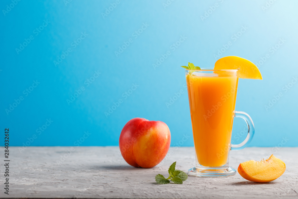Glass of peach juice on a gray and blue background. Side view Glass of peach juice on a gray and blue background. Side view