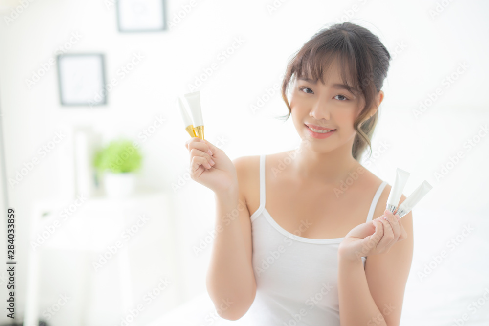 Beautiful portrait young asian woman holding and presenting cream or lotion product, beauty asia girl show cosmetic makeup and moisturizing for skin care, healthy care and wellness concept. Beautiful portrait young asian woman holding and presenting cream or lotion product, beauty asia girl show cosmetic makeup and moisturizing for skin care, healthy care and wellness concept.