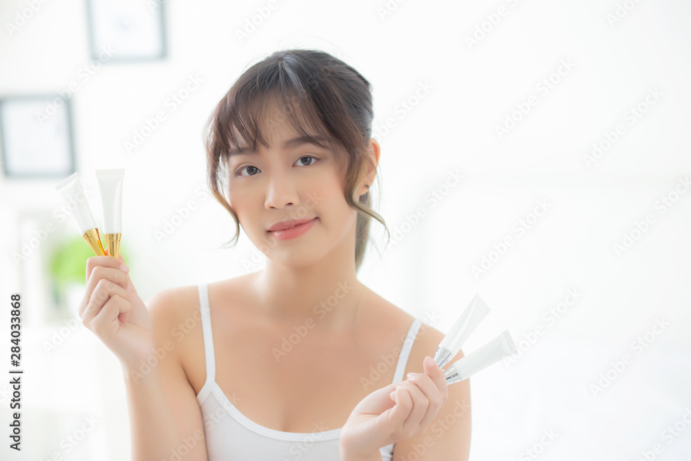 Beautiful portrait young asian woman holding and presenting cream or lotion product, beauty asia girl show cosmetic makeup and moisturizing for skin care, healthy care and wellness concept. Beautiful portrait young asian woman holding and presenting cream or lotion product, beauty asia girl show cosmetic makeup and moisturizing for skin care, healthy care and wellness concept.