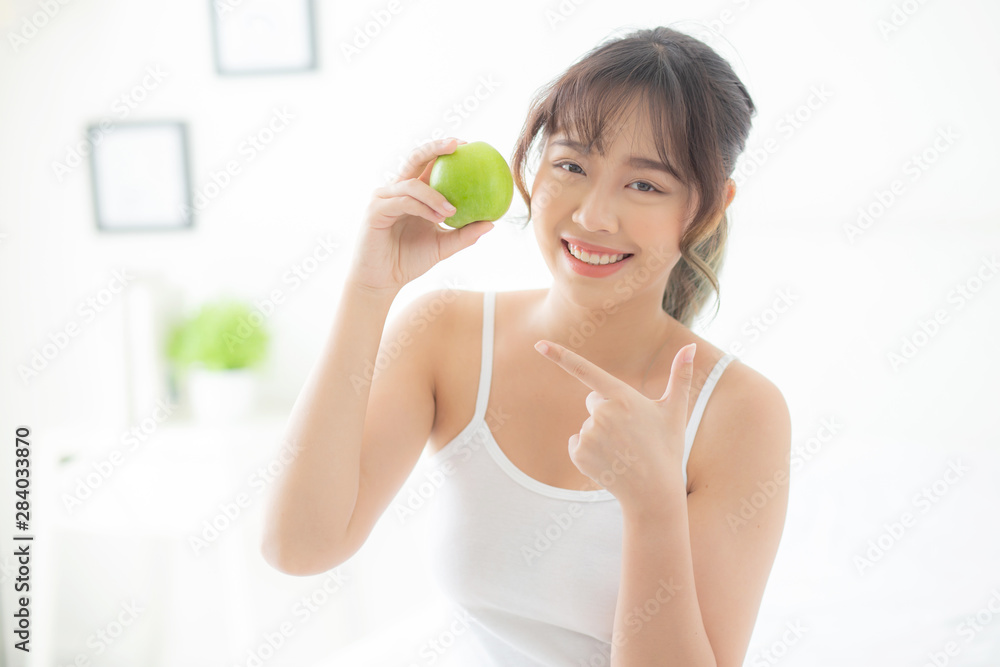 Beautiful portrait young asian woman holding and pointing green apple fruit in the bedroom at home, lifestyle of nutrition girl healthy and care weight loss, health and wellness concept. Beautiful portrait young asian woman holding and pointing green apple fruit in the bedroom at home, lifestyle of nutrition girl healthy and care weight loss, health and wellness concept.