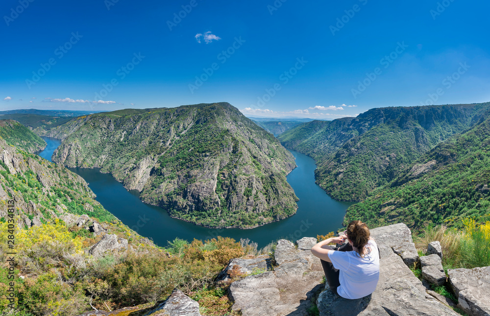 A woman contemplates the incredible Sil Canyon in the Ribeira Sacra from a fabulous viewpoint where she can see a meander of the Sil river