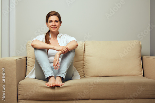 Smiling casual dressed girl sitting on couch.